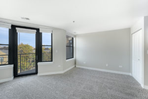bright carpeted room with large windows facing balcony